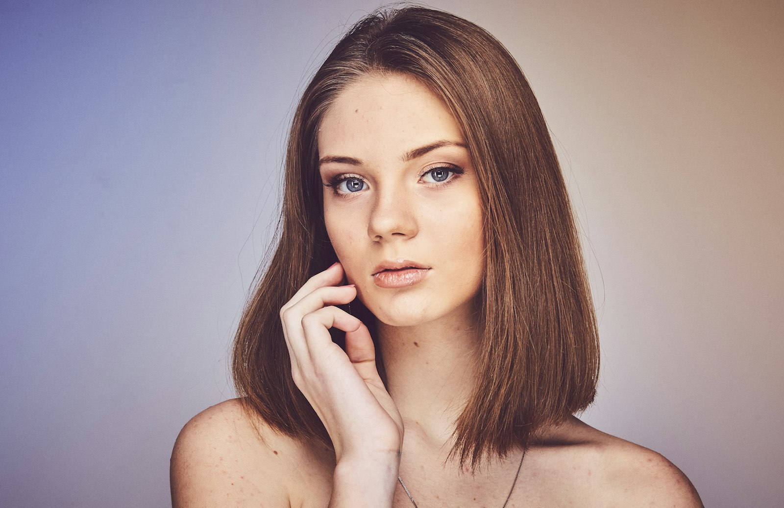 A portrait of a woman with a shoulder-length brown bob against a pale background